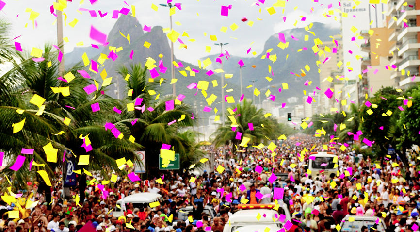 Foto do bloco na praia de Ipanema, no meio da rua, tirada de cima, com confetes voando.